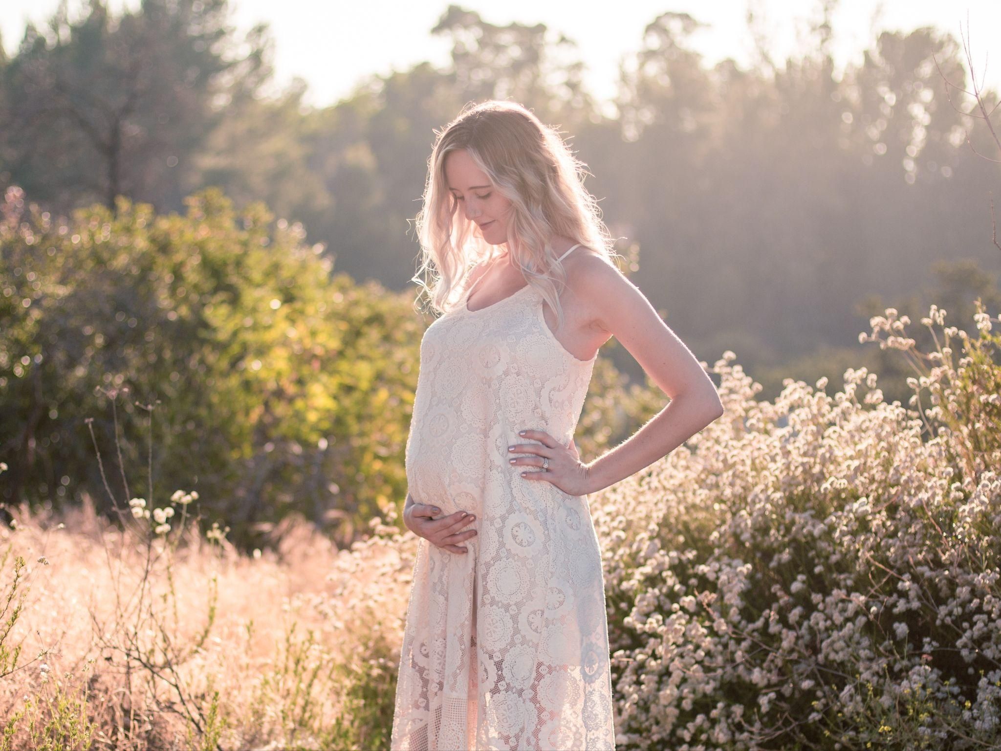 A pregnant woman posing in a beautiful natural landscape during a maternity photography session in London.