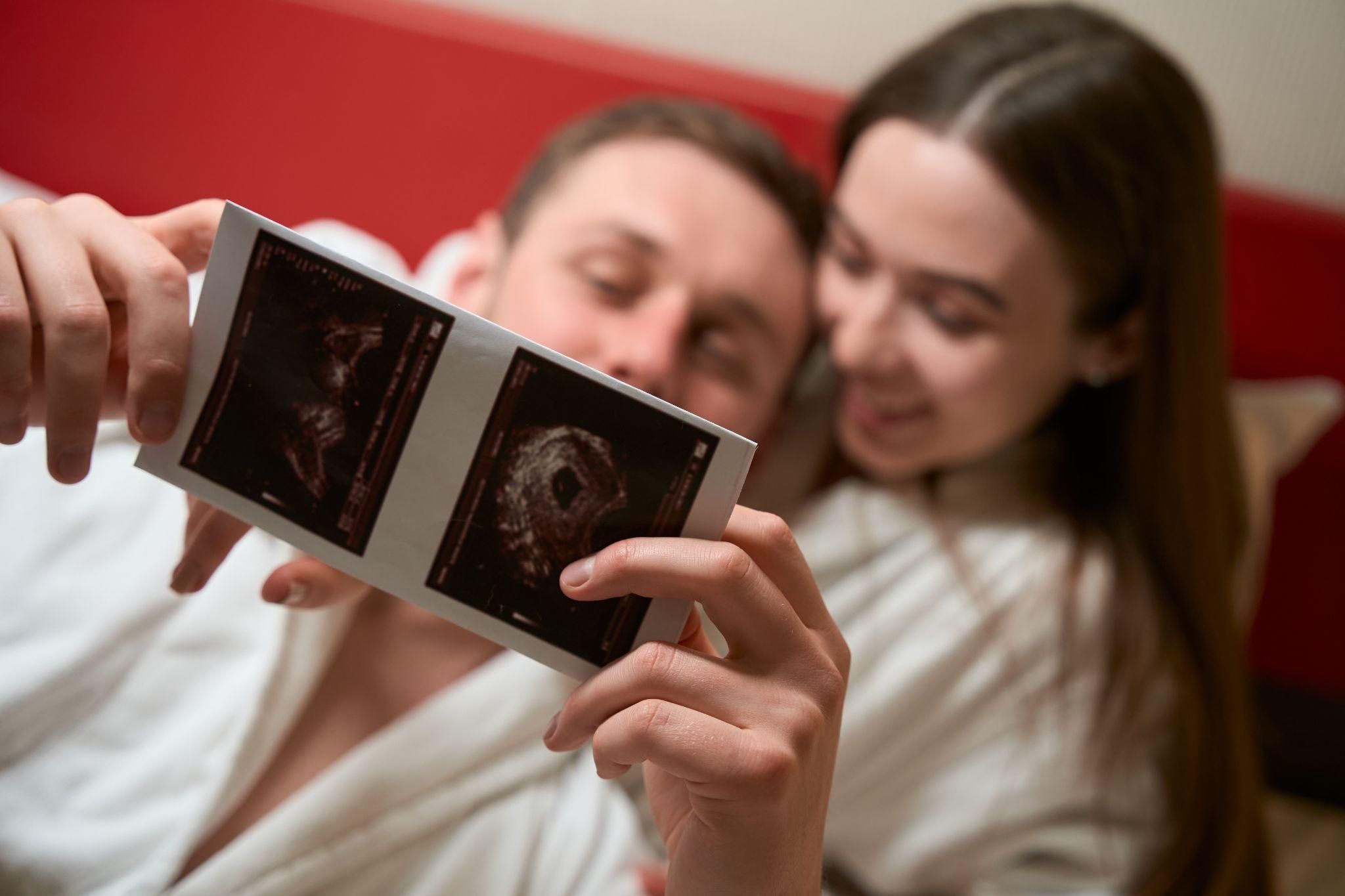 Expectant parents holding a baby ultrasound image.