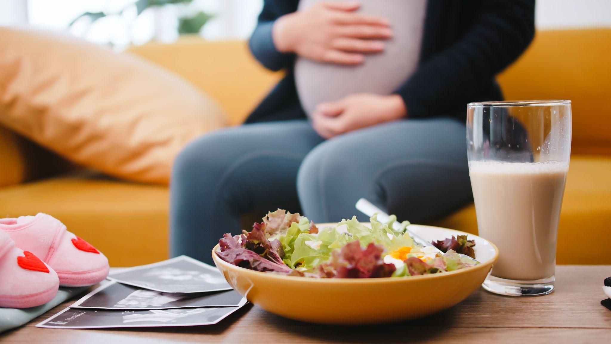 Pregnant woman enjoys a smoothie and a salad as part of her antenatal diet.