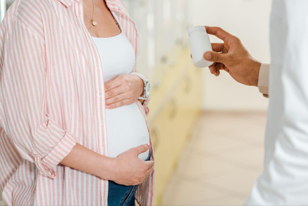 Pregnant woman in shop speaks to pharmacist about the best antenatal vitamins.