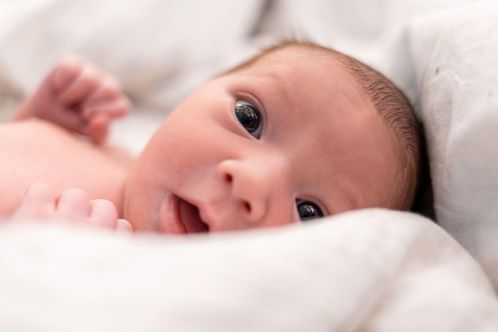 Healthy newborn baby girl’s eyes are open wide.