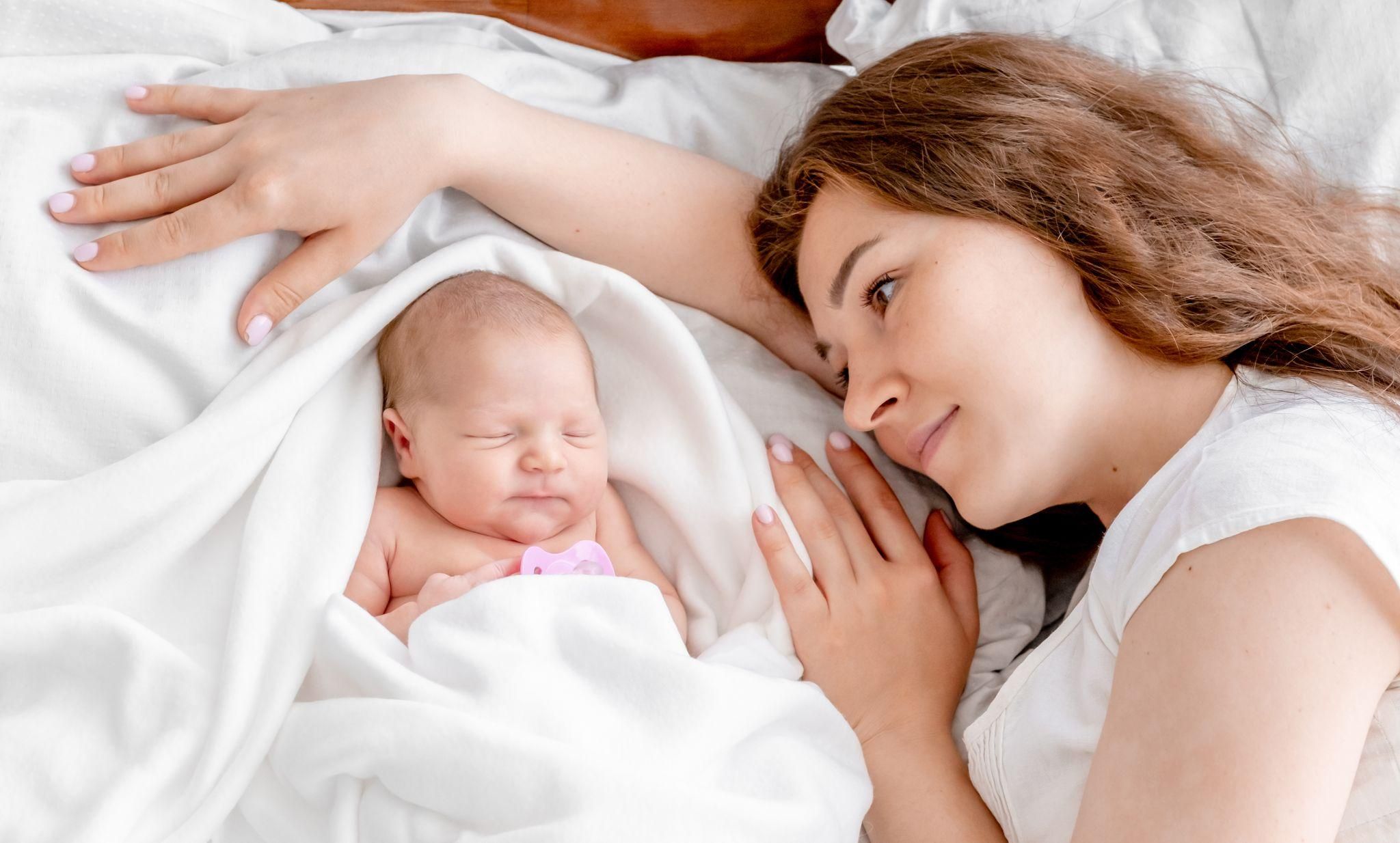 A two-week-old baby sleeping soundly in a swaddle at night.