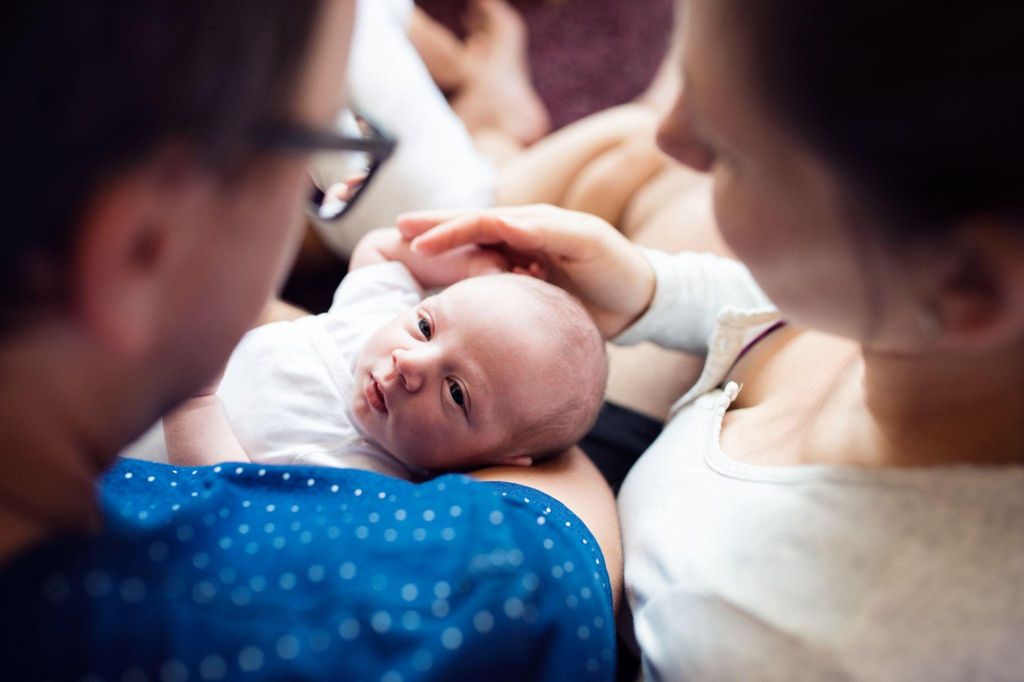 Newborn baby being held by a parent after feeding, with gentle care.