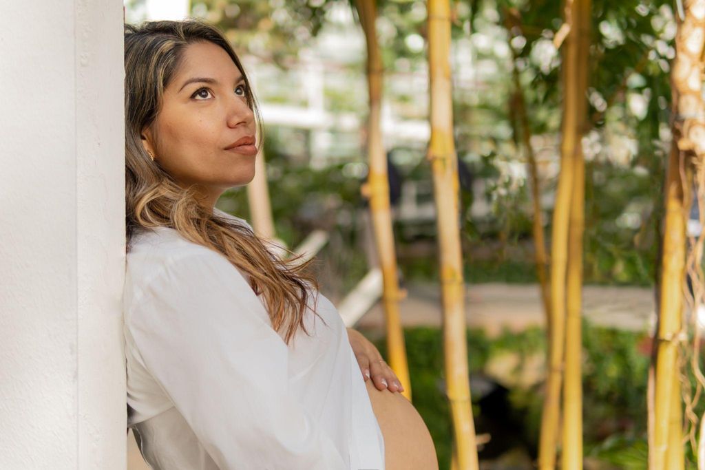 Pregnant woman sitting peacefully in a yoga pose, looking content and relaxed.