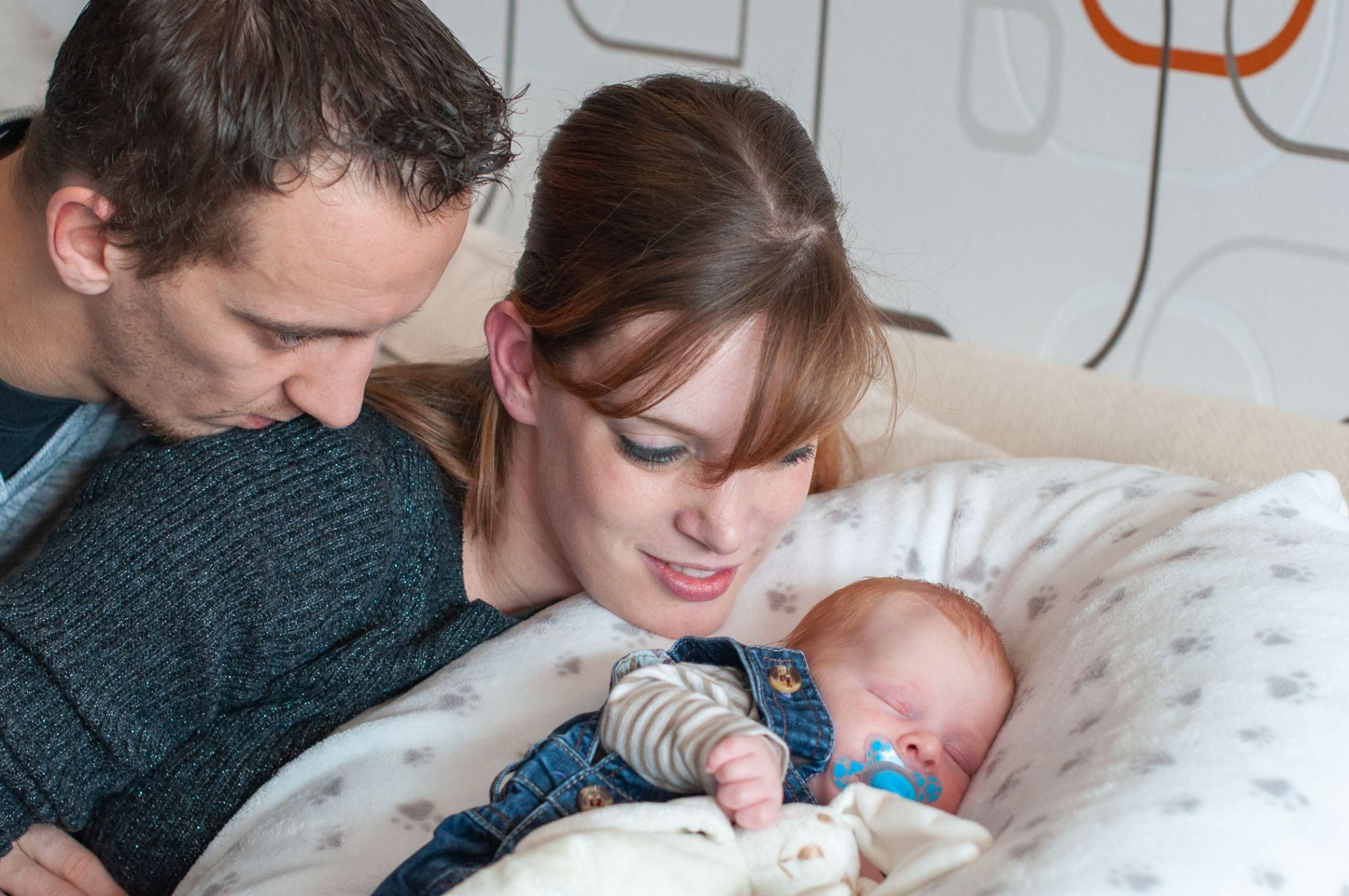 Happy parents with sleeping newborn.