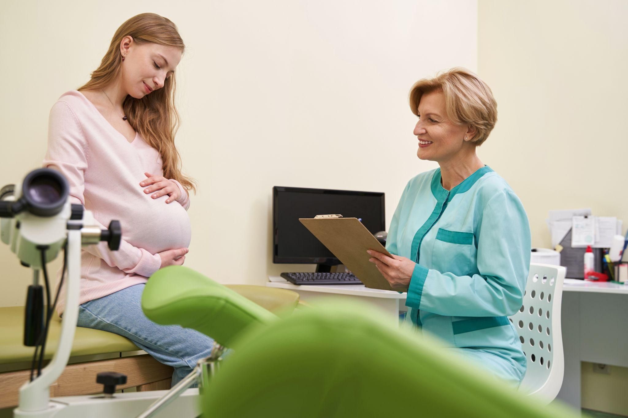 Pregnant woman works with a female obstetrician to write her birth plan during a routine antenatal care appointment.