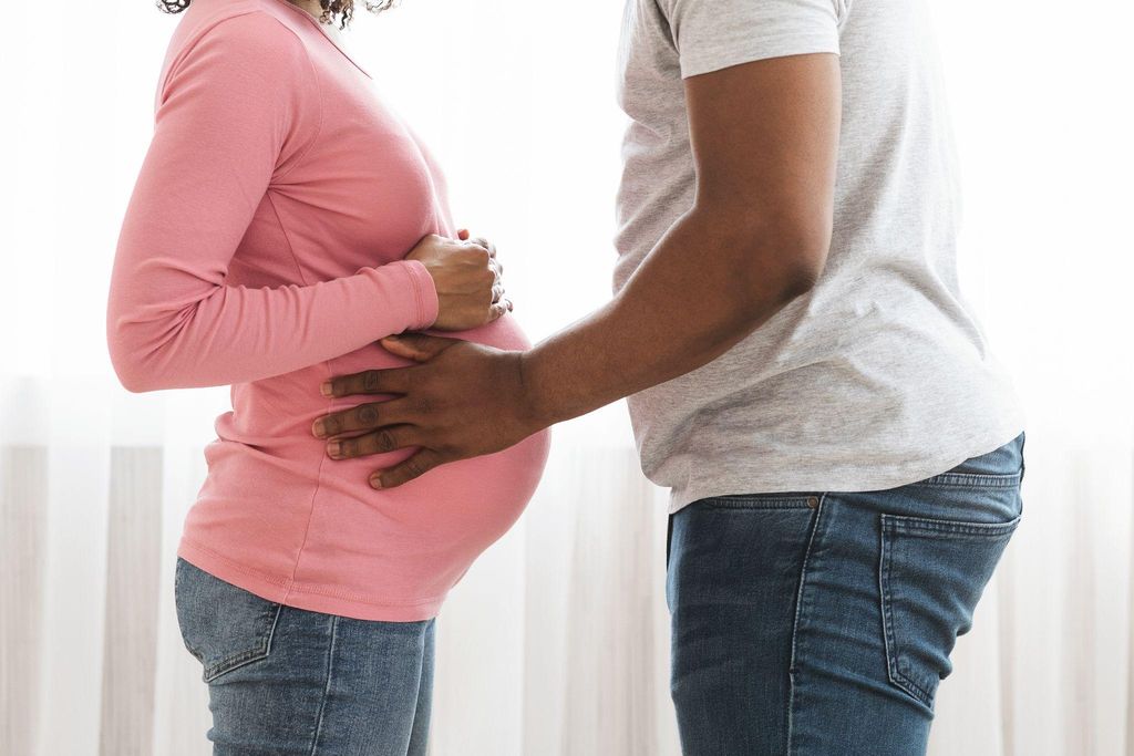 Man holds pregnant lady’s bump.