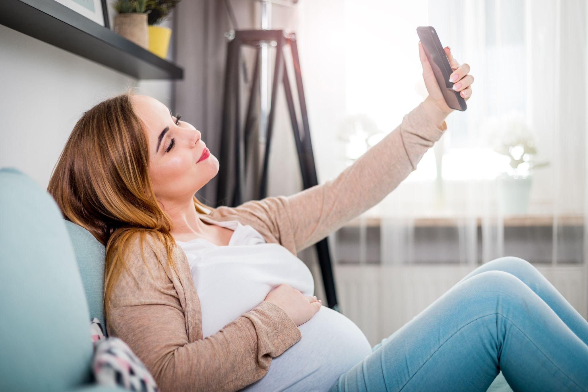 Pregnant woman taking selfies at home.