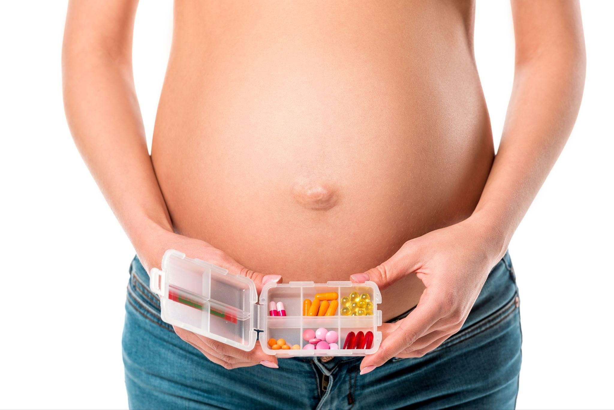 Pregnant woman discusses vitamins and supplements with pharmacist.