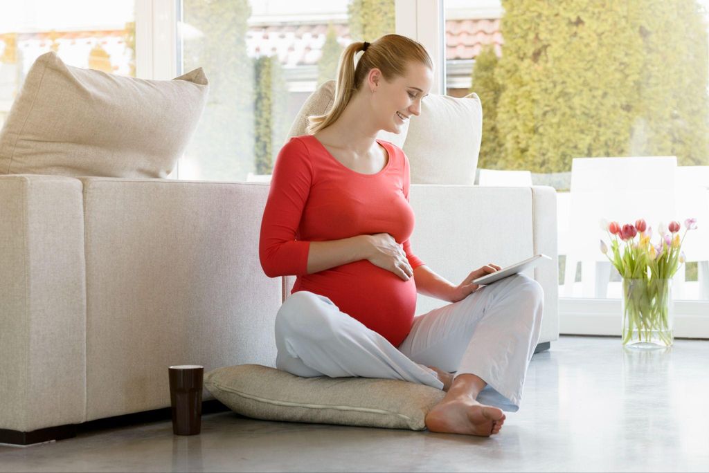 A pregnant woman learning about pregnancy myths while smiling.