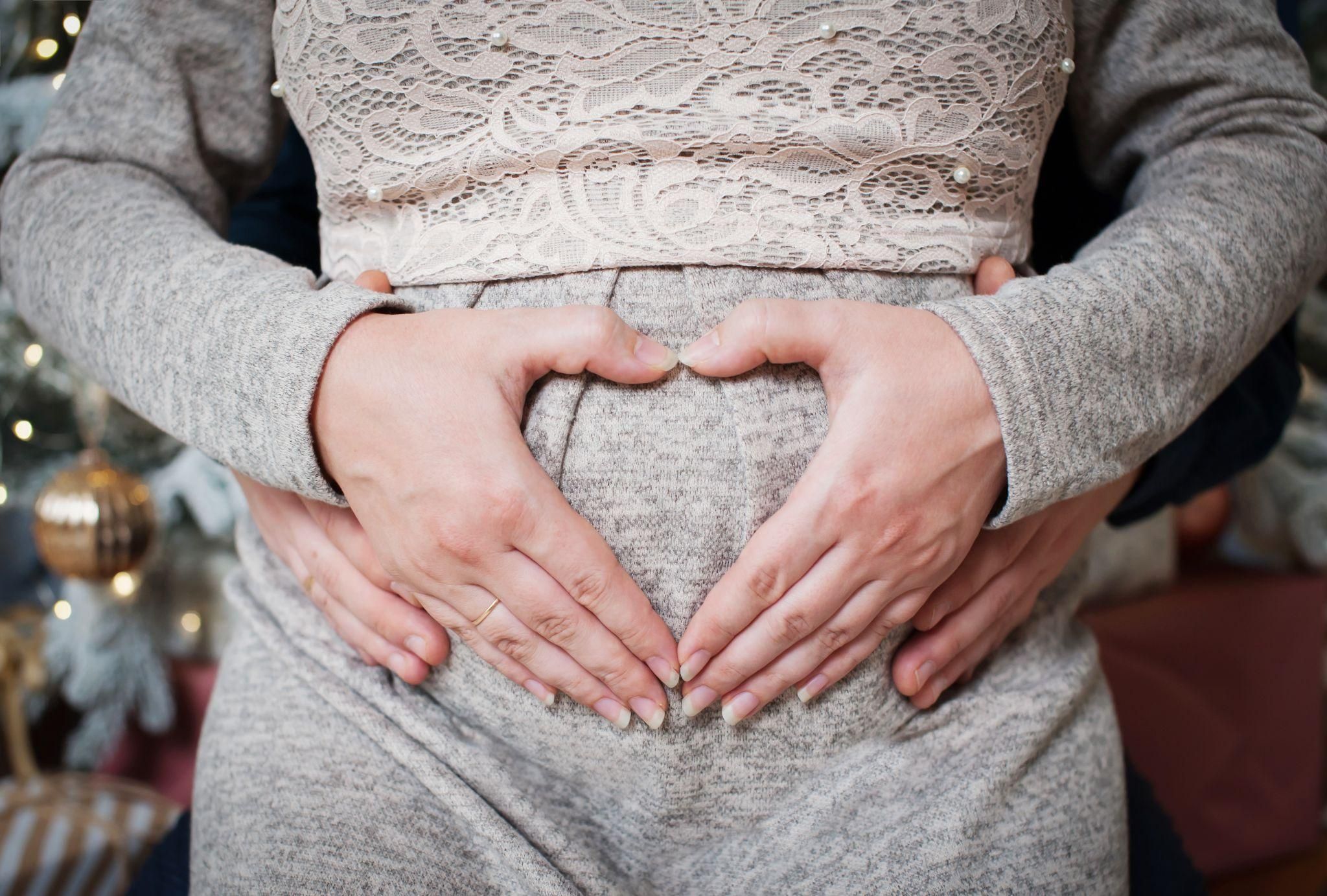 A woman in the final stages of pregnancy feeling her baby drop lower into the pelvis.