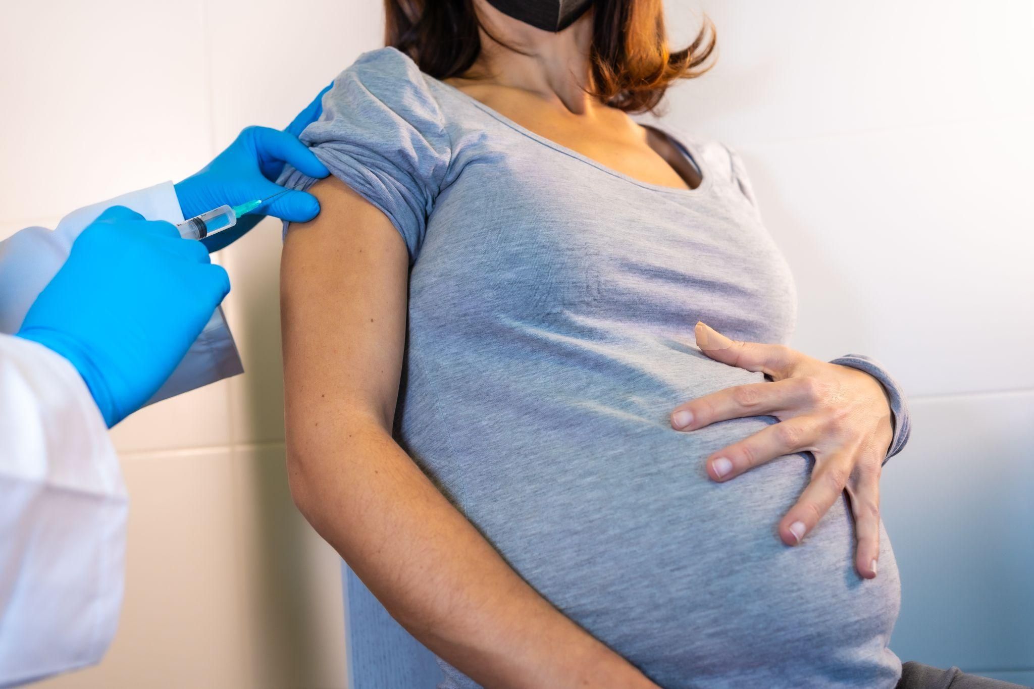 A nurse giving a pregnant woman an injection during a routine antenatal checkup.