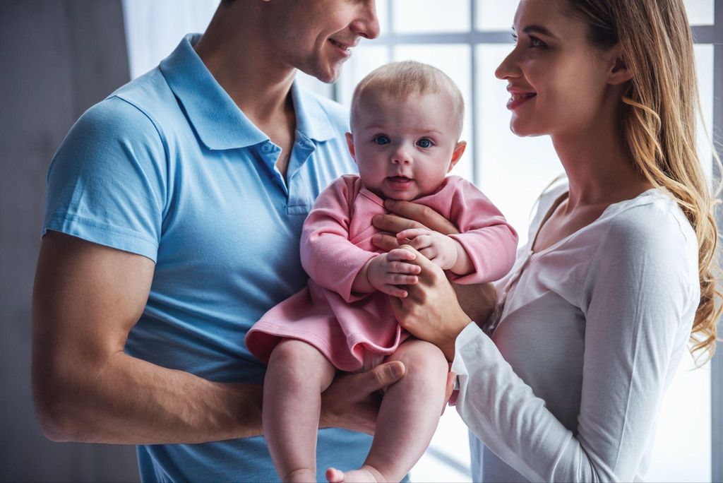 A happy couple bonding with their baby in a cosy home environment.