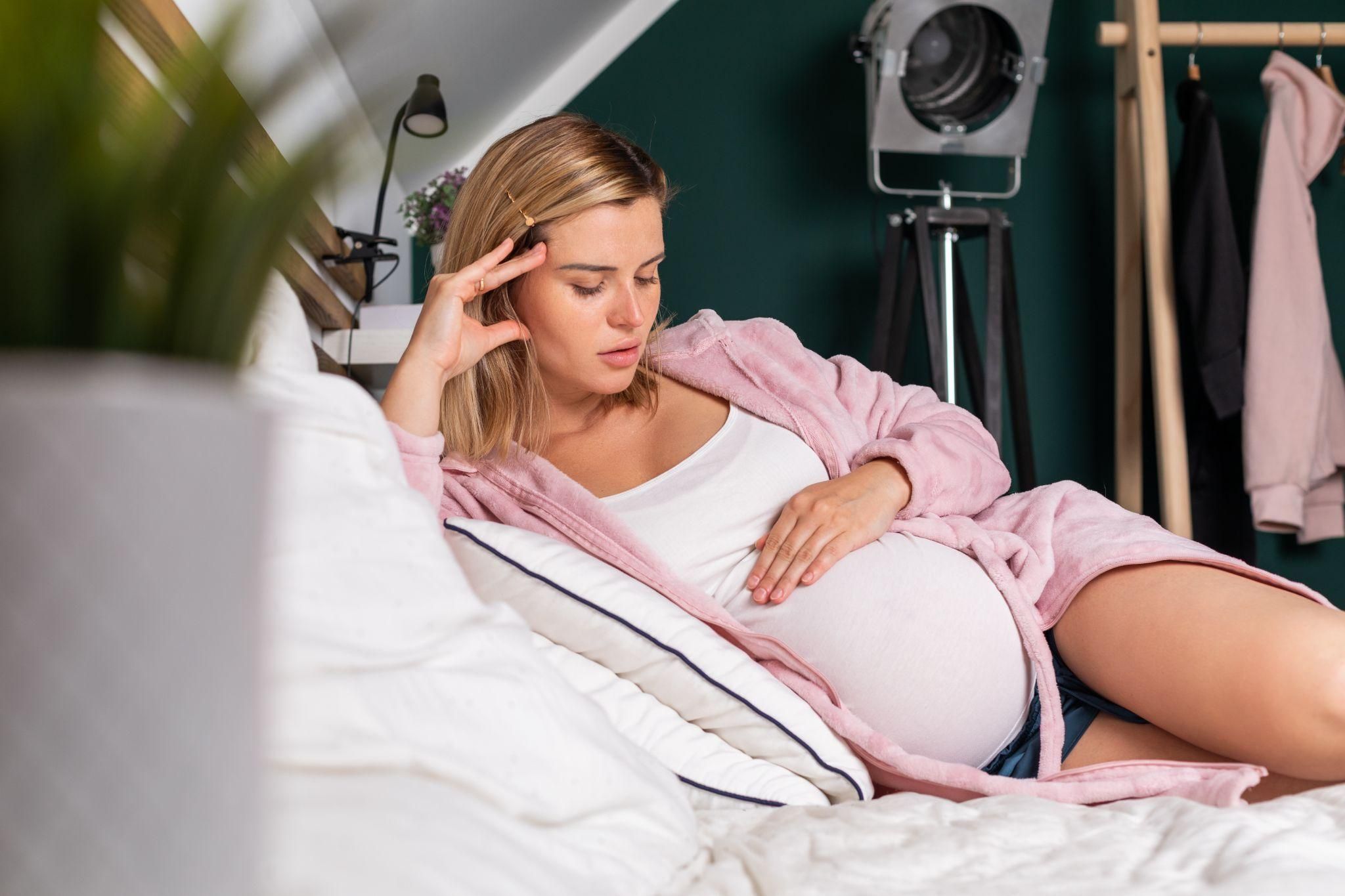 Pregnant woman lying on her side and worrying about her baby.