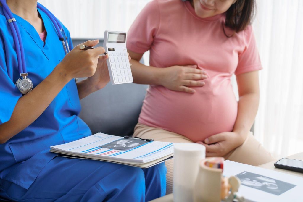 A smiling pregnant woman with a midwife during an antenatal checkup.