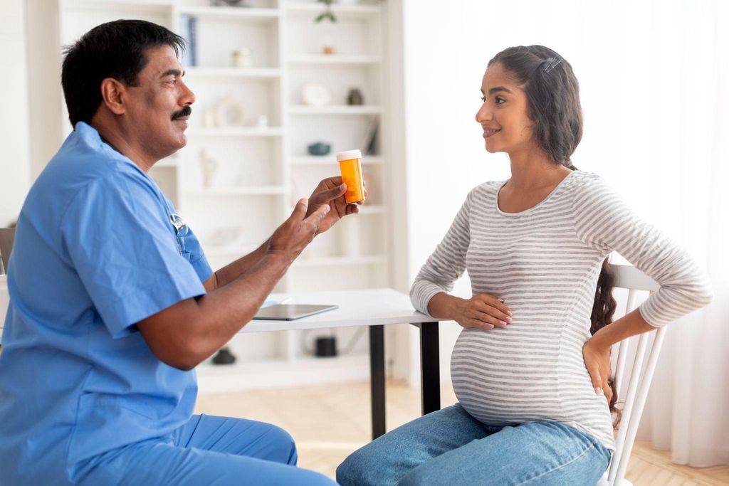 Pregnant woman talking to male midwife about vitamins and her antenatal health.