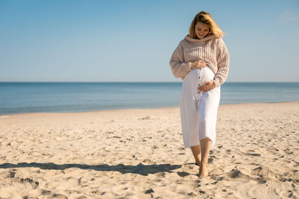 "Pregnant woman relaxing on a beach during her late pregnancy, preparing for a safe holiday."