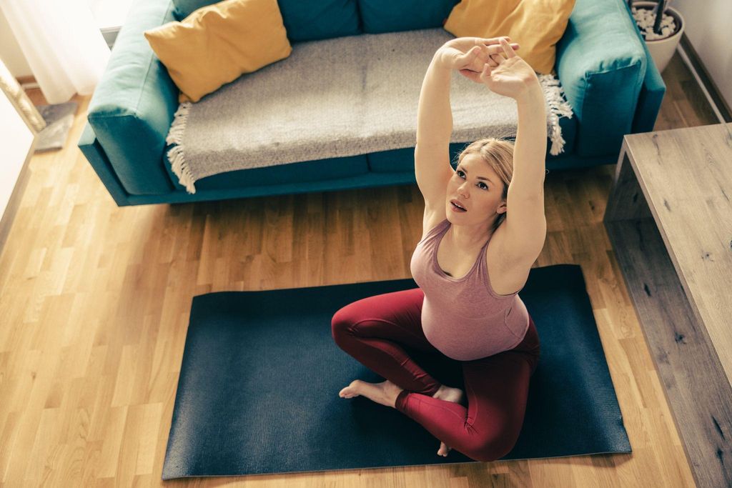 Pregnant woman doing yoga for pregnancy to ease wind and bloating.