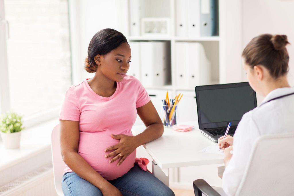 A woman with a growing baby bump at an antenatal care appointment.