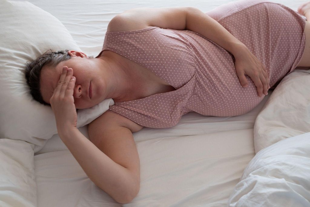 A pregnant woman lying in bed and suffering from antenatal stress.