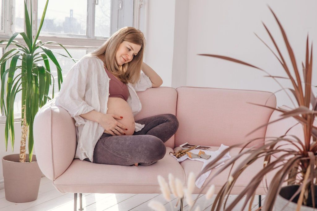 A smiling pregnant woman bonding with her baby bump through touch and relaxation.