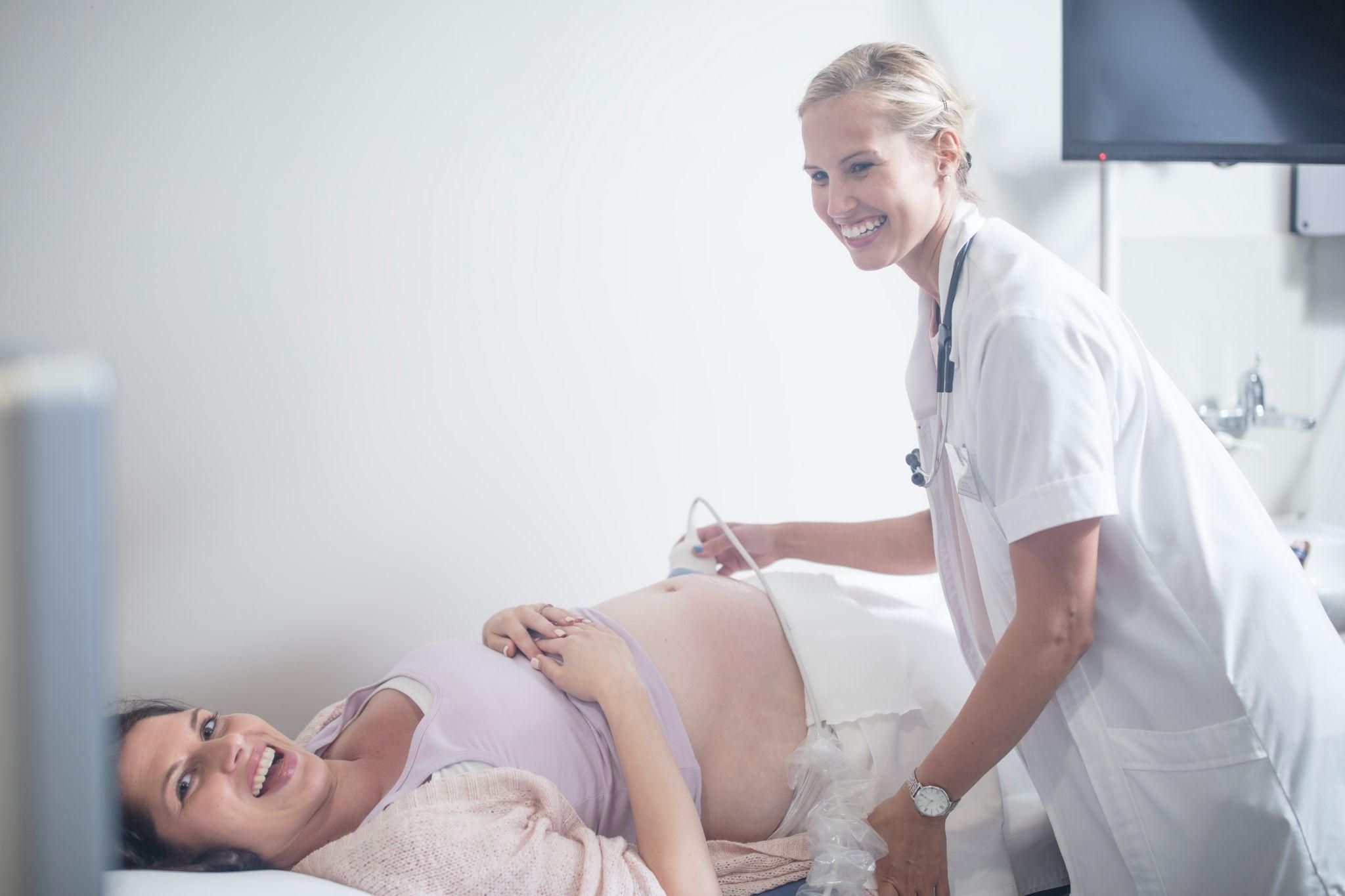 Pregnant woman using breathing techniques during labour with the guidance of a midwife.