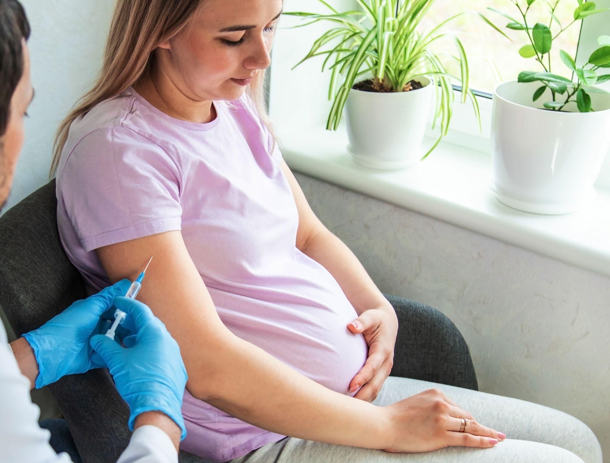 Pregnant woman receives vaccination from doctor during a routine appointment at her antenatal clinic. Pregnancy vaccines include flu, COVID-19, RSV and pertussis (whooping cough).