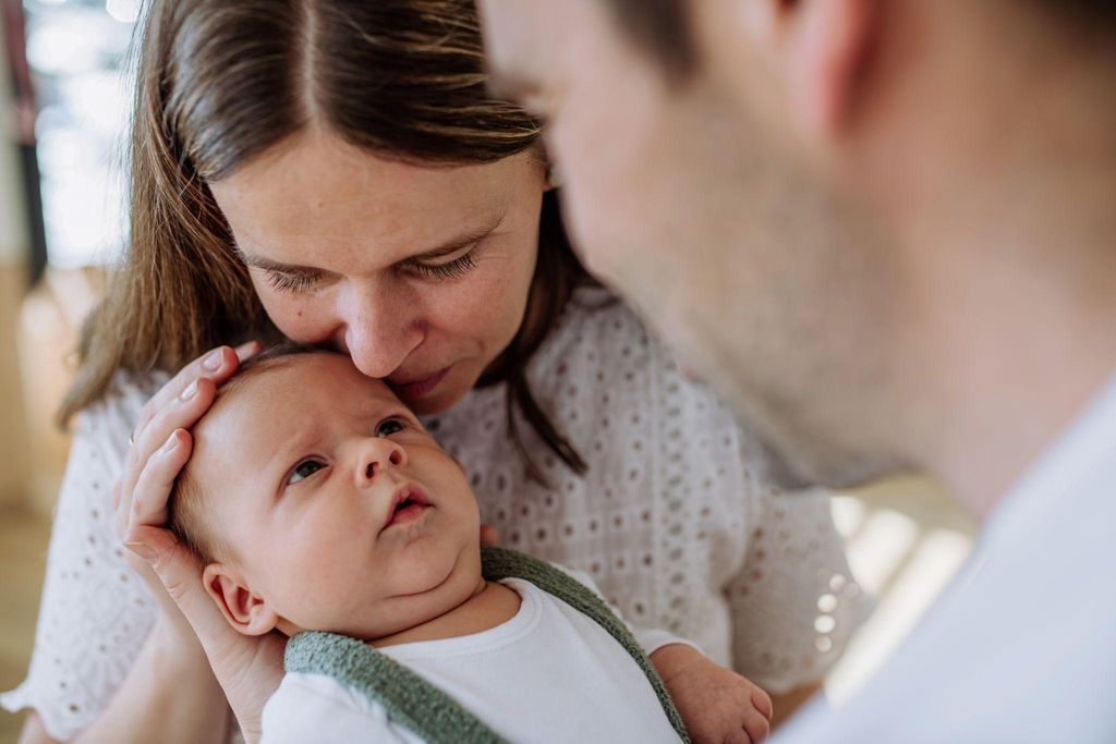 A happy couple bonding with their newborn in a cosy home environment.