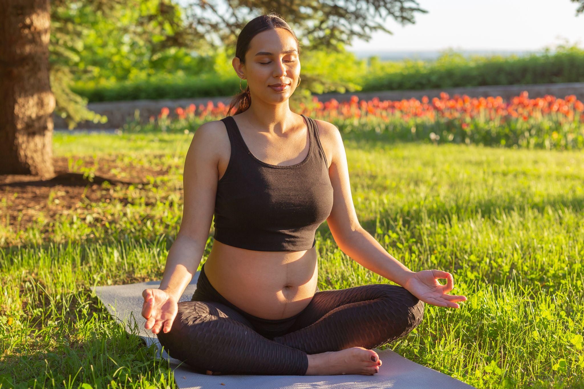 A pregnant woman sitting cross-legged, practising antenatal breathing for relaxation.