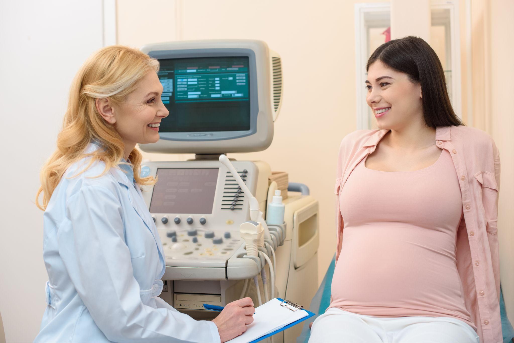 Woman happily discusses her gestational health with her obstetrician during the second trimester of her pregnancy.