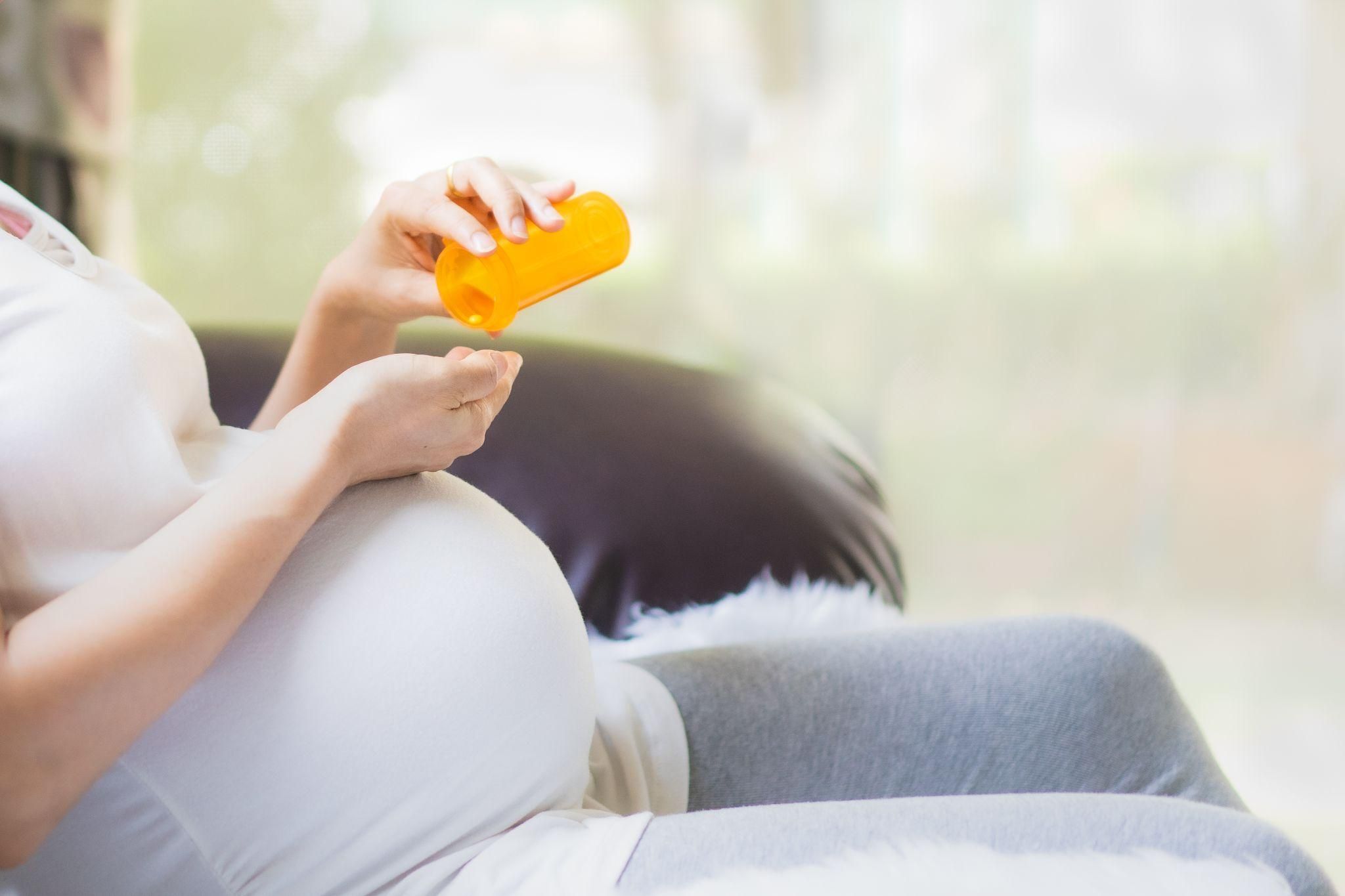 Pregnant woman checking over-the-counter medication for safety during pregnancy.