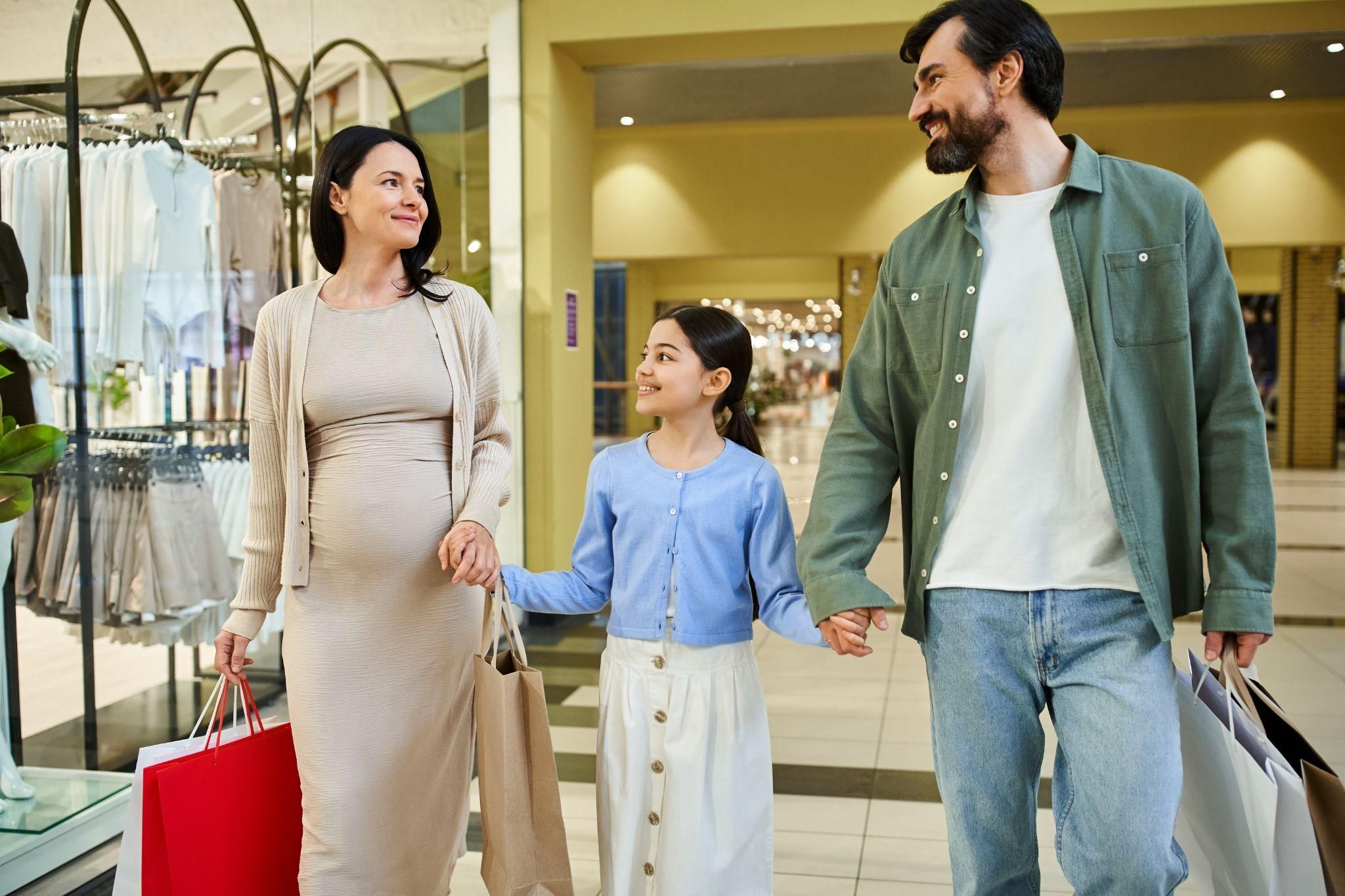 Pregnant woman shopping with partner and daughter.