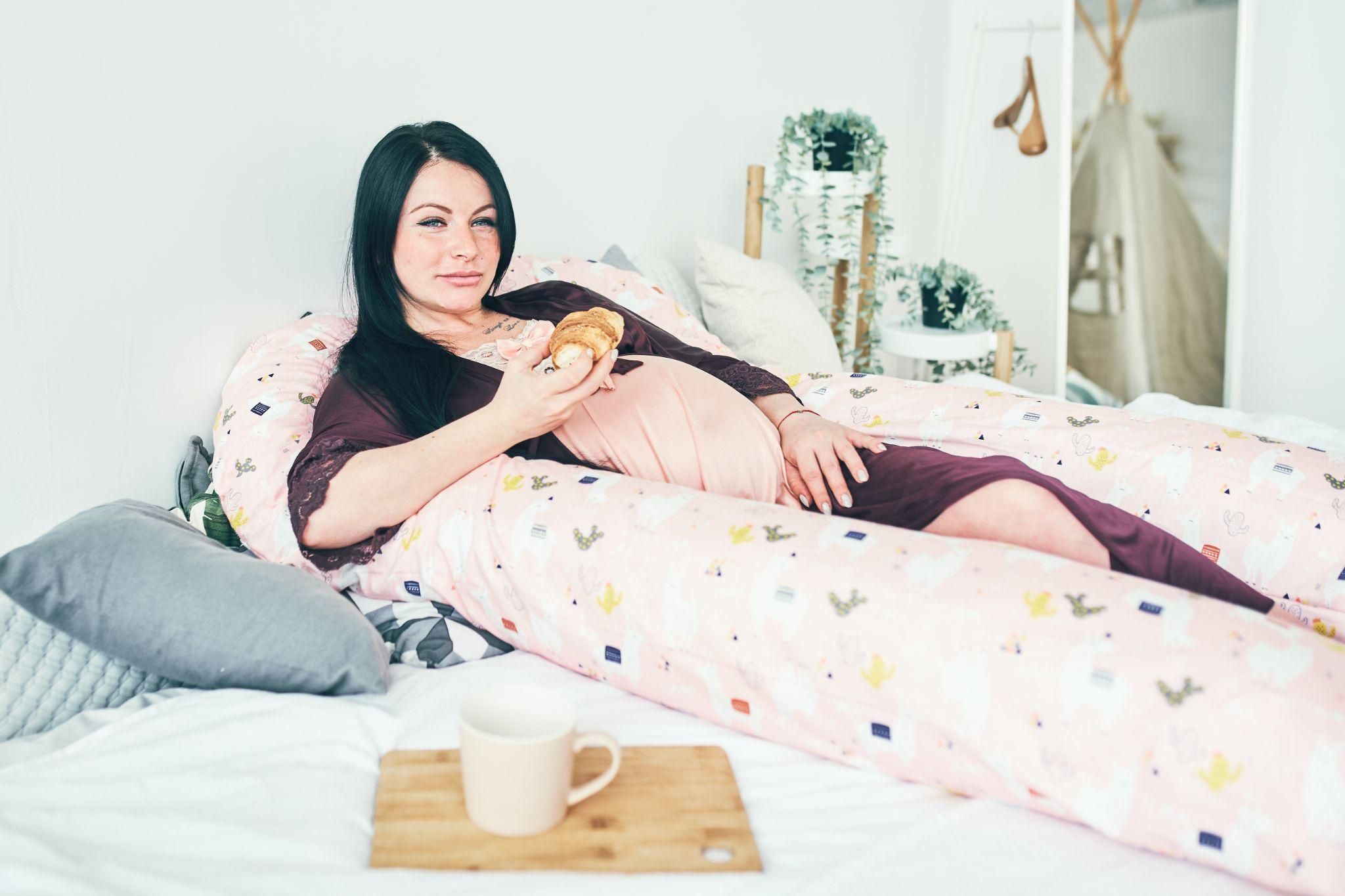 A pregnant woman relaxing with a pregnancy pillow for better sleep support.