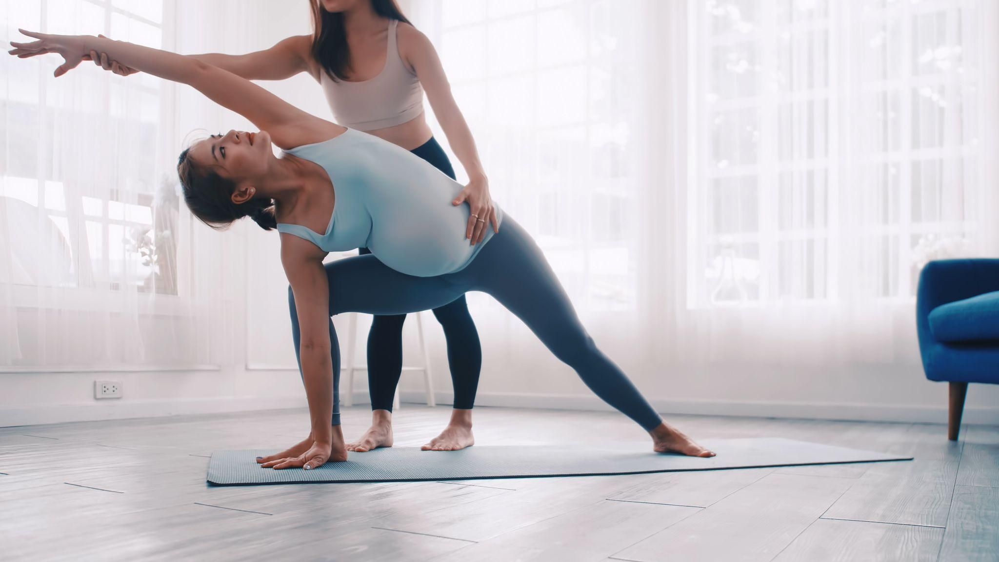 A pregnant woman performing yoga stretches and breathing techniques in a peaceful setting to prepare for natural pain relief during labour.