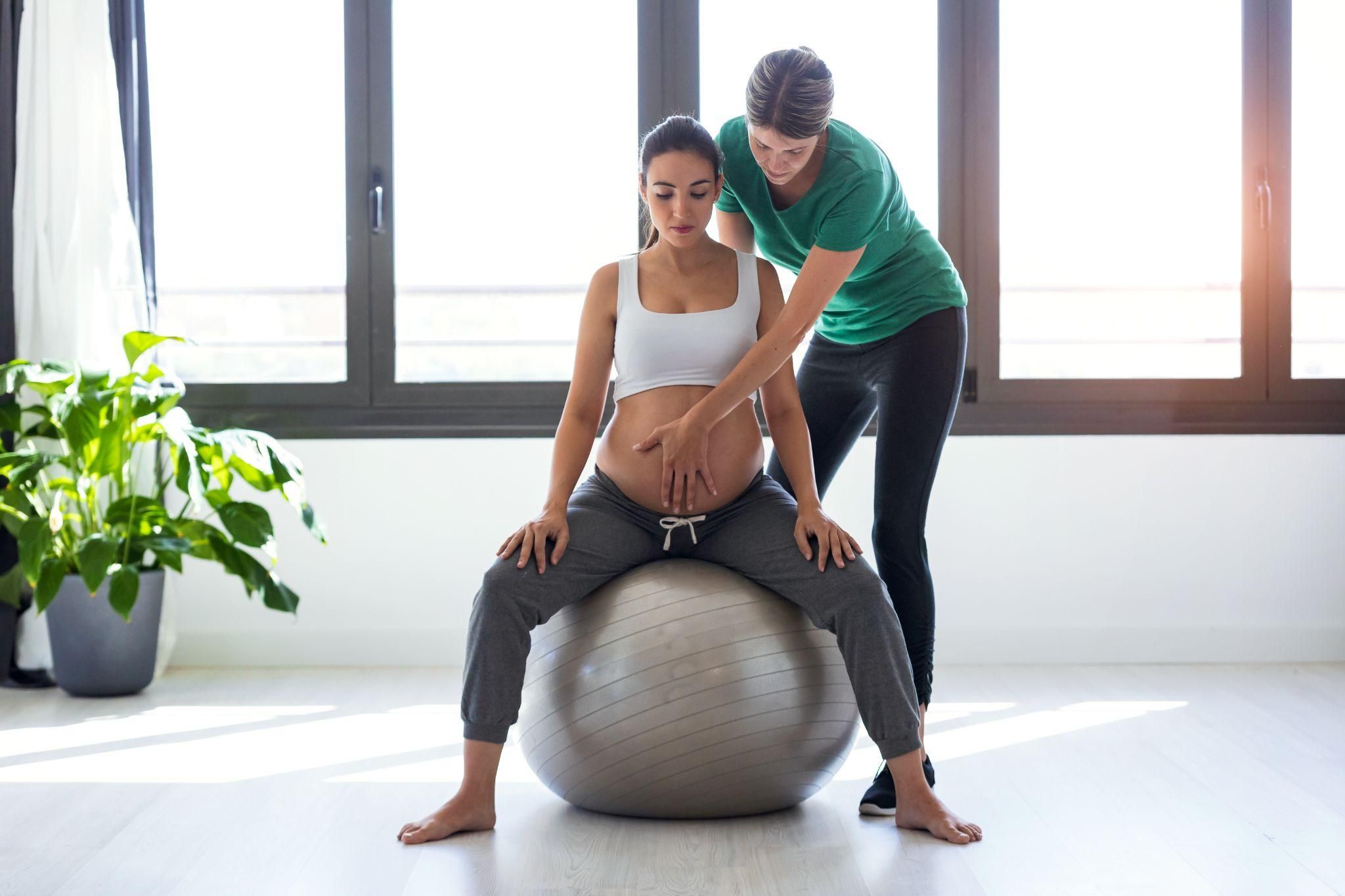 A physiotherapist assisting a pregnant woman with antenatal exercises.