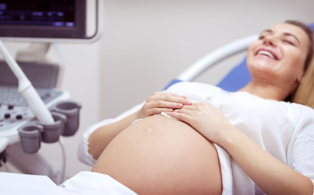 Pregnant woman in labour with her partner and midwife, making informed decisions about her birth rights.