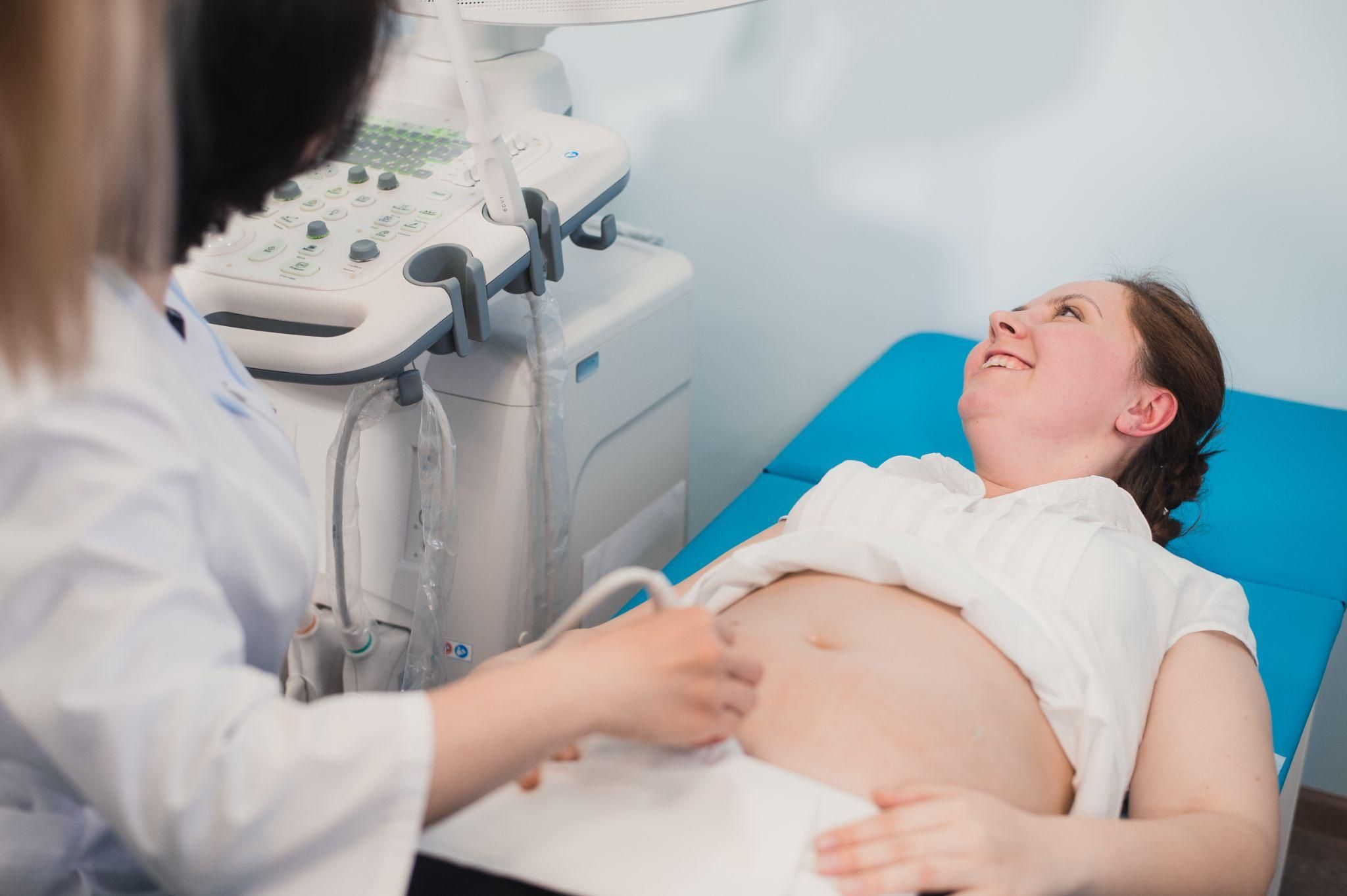 A pregnant woman receiving an ultrasound scan during her first antenatal appointment.