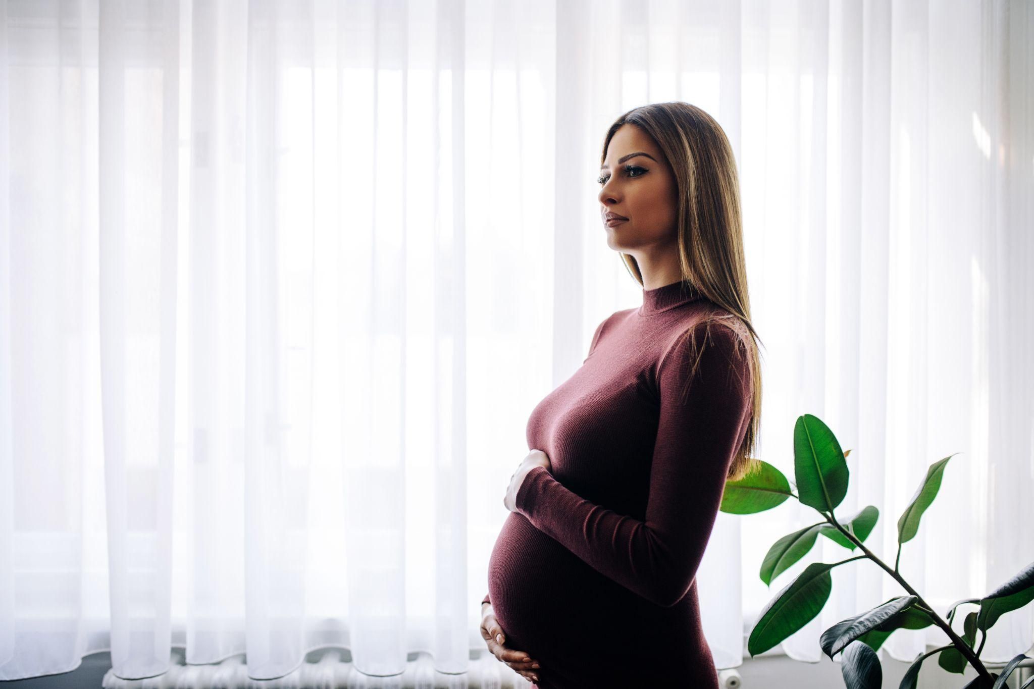 Pregnant lady smiling in a figure-skimming dress.