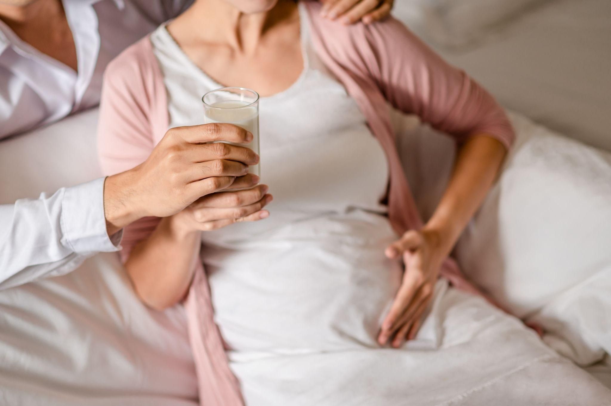 Pregnant woman practising relaxation techniques and sipping water to relieve morning sickness at night.