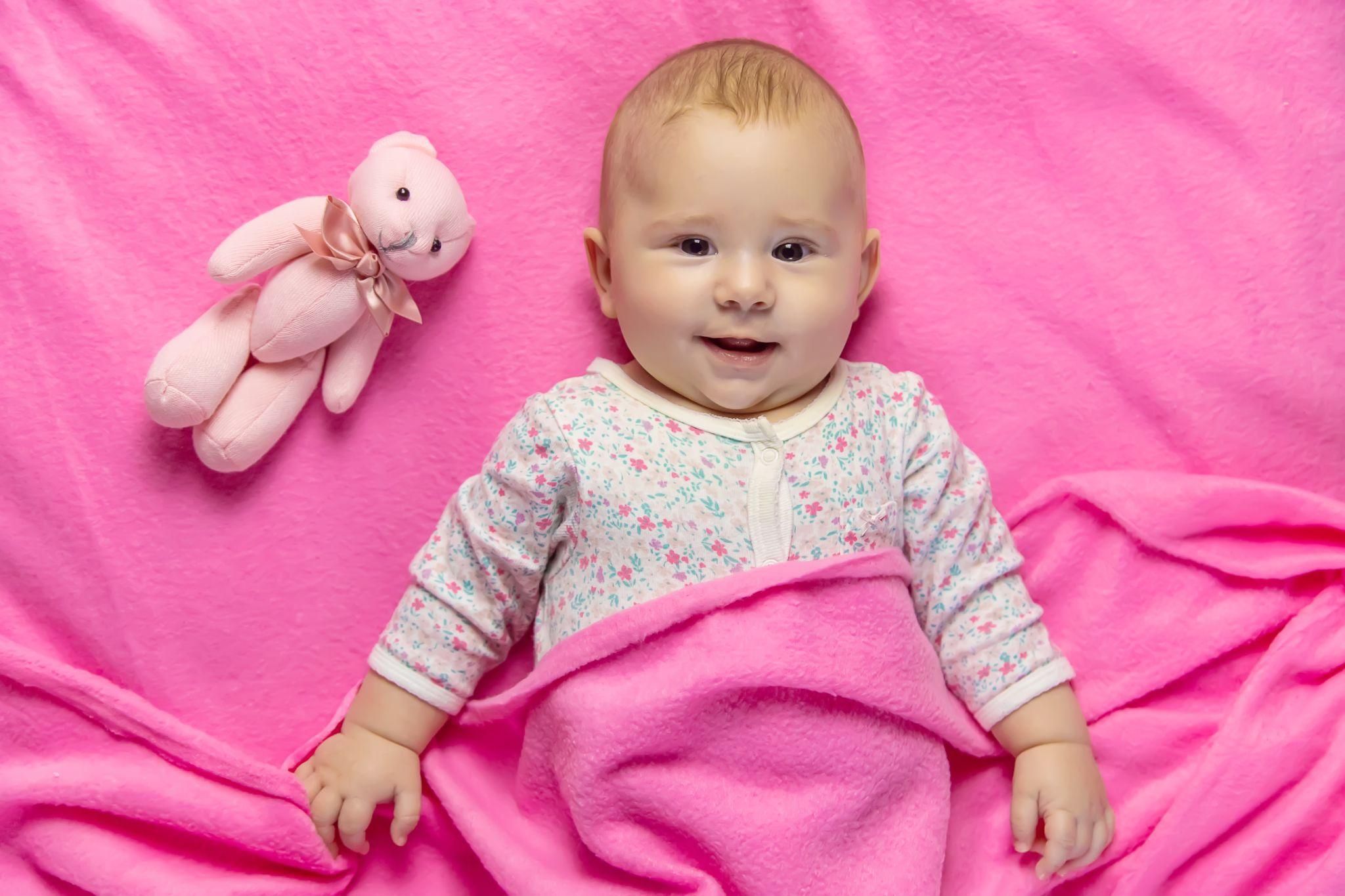 Baby blankets in different textures and colours arranged in a cosy nursery setting.