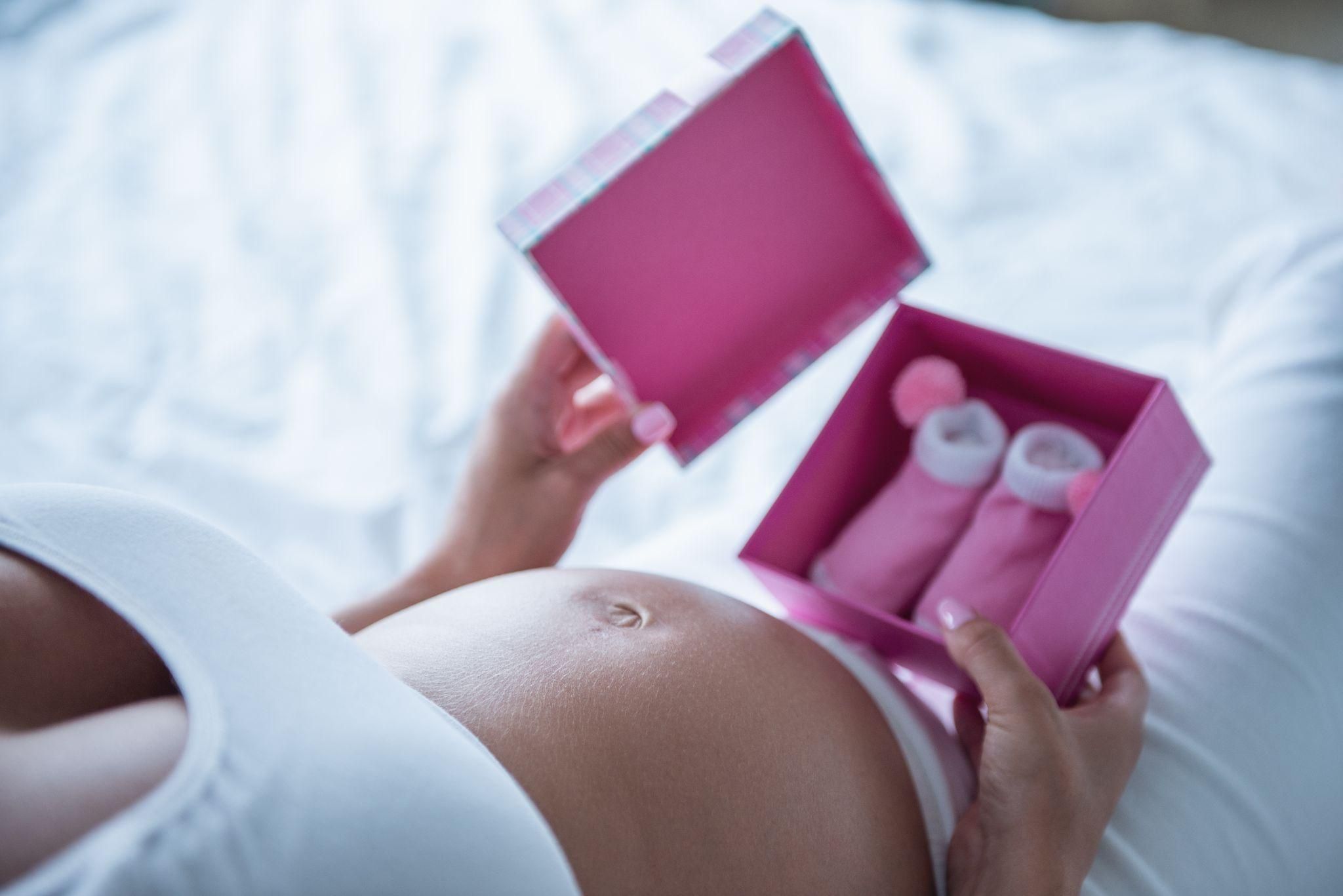 Pregnant woman opening baby shower gift.