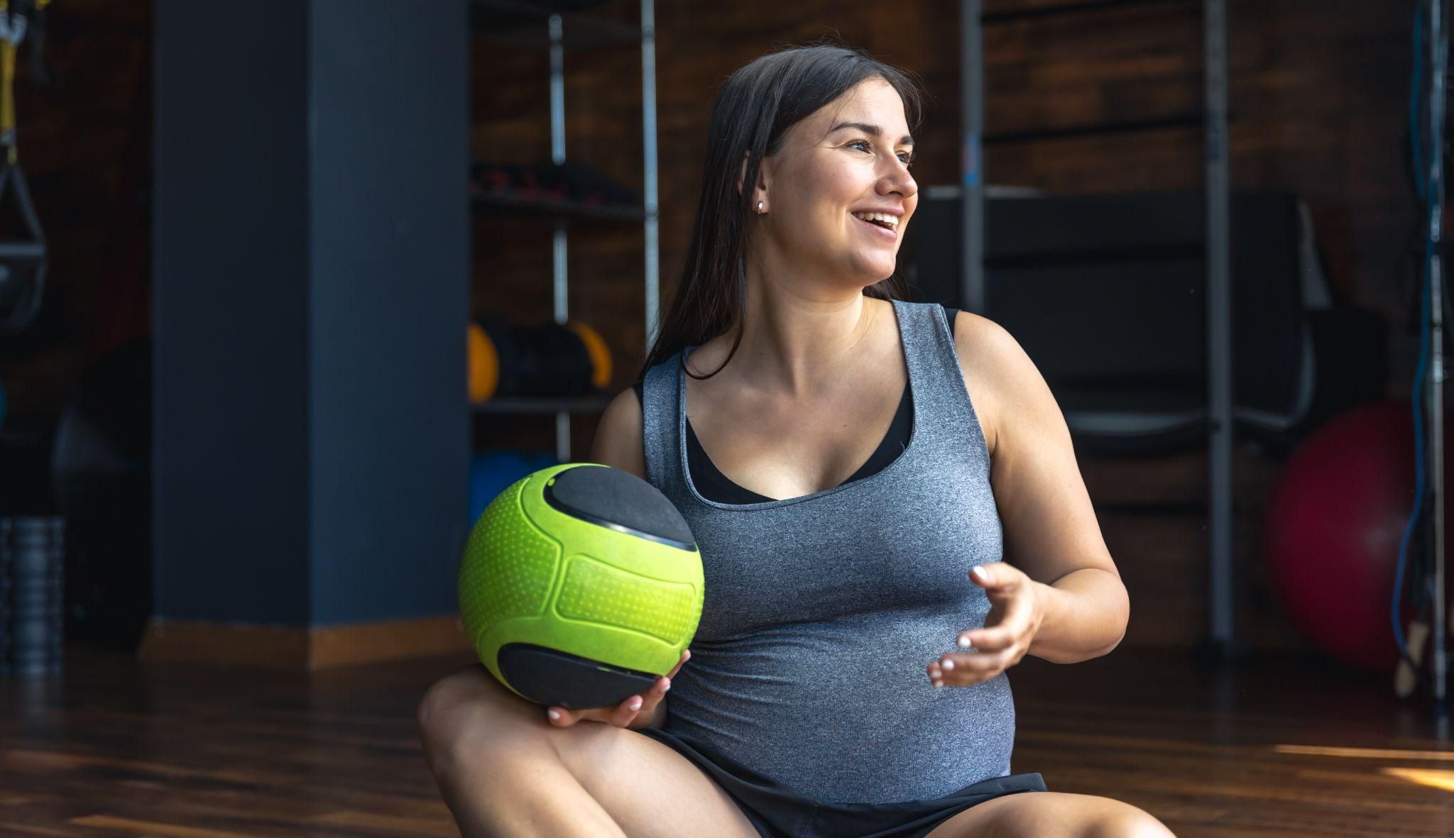 A pregnant woman practising gentle yoga poses, focusing on antenatal fitness.