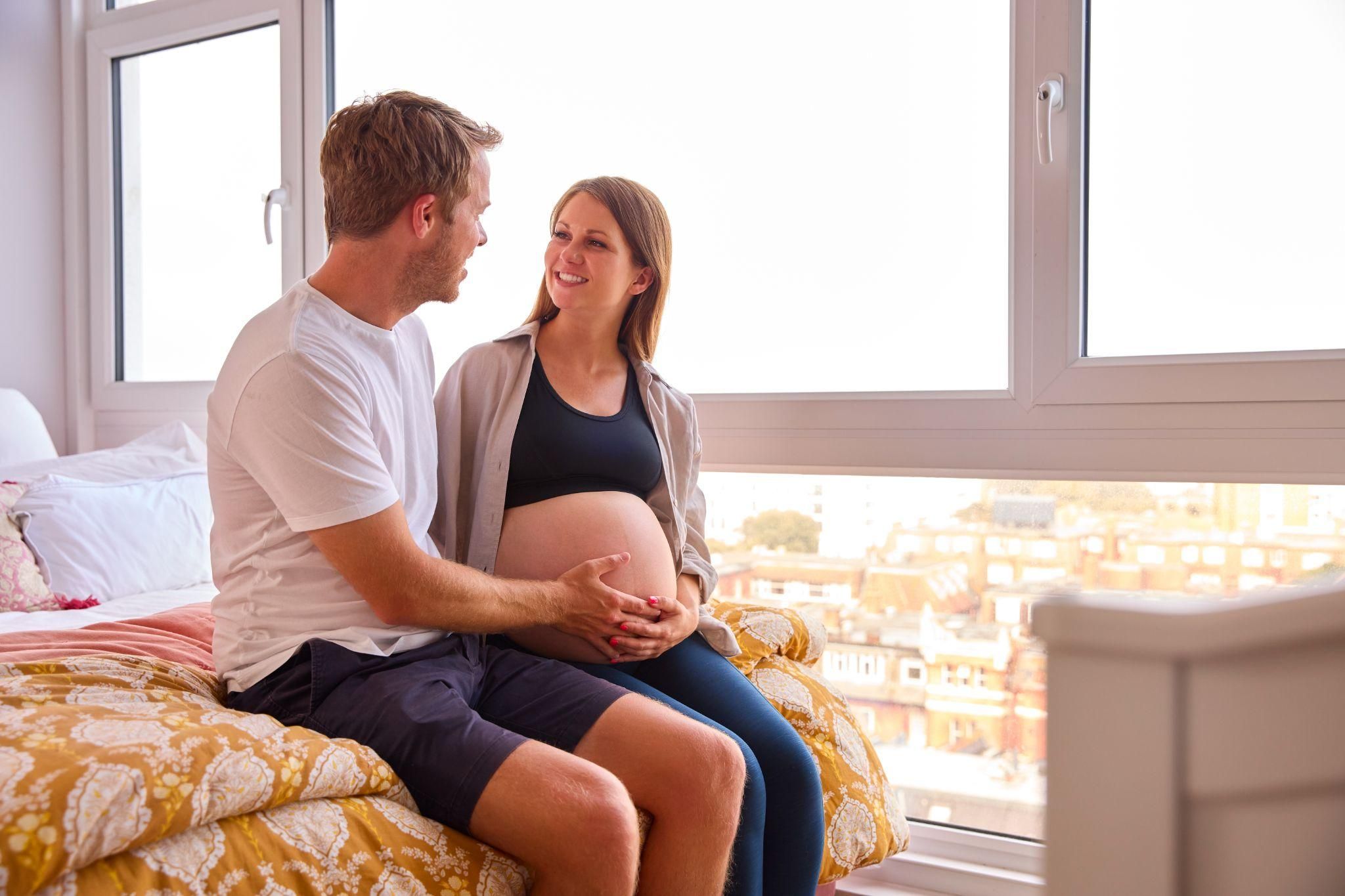 A pregnant couple sharing a moment of intimacy and connection at home.