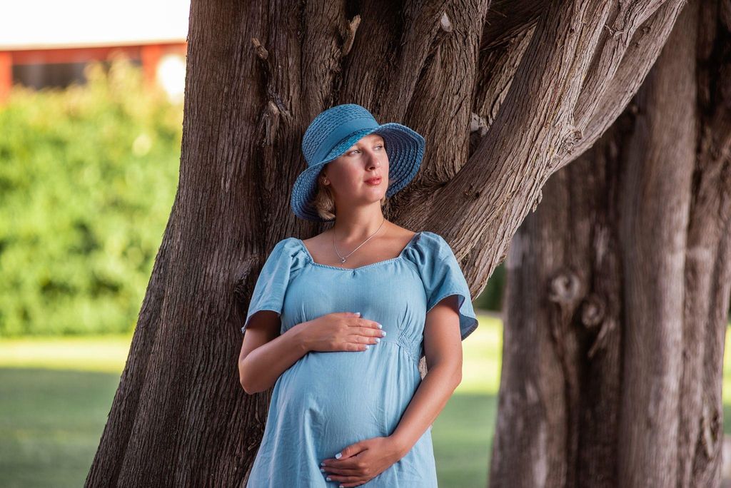 Pregnant woman feeling isolated, sitting alone while her supportive partner is nearby.