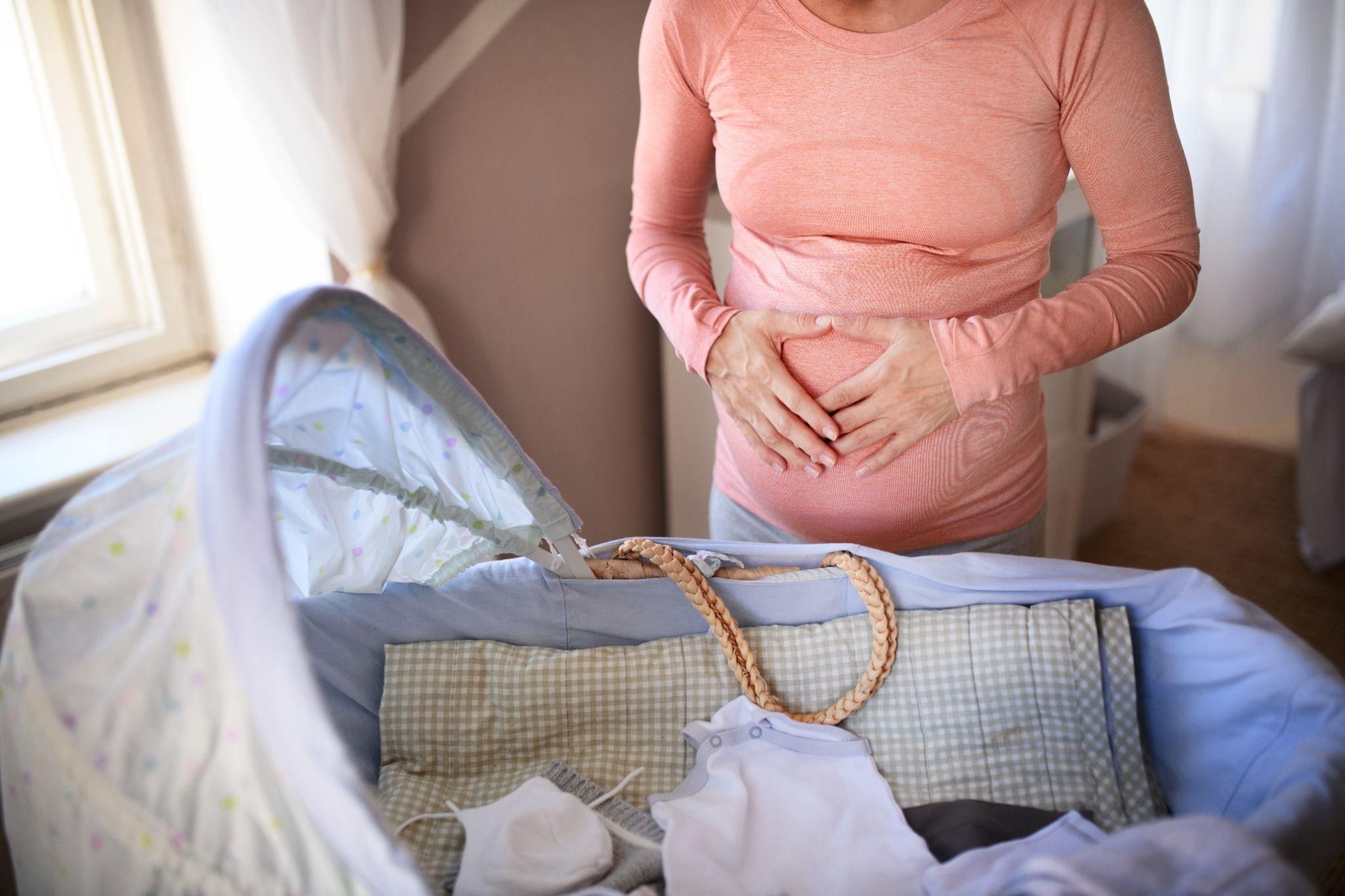 Pregnant lady with hands on baby bump.