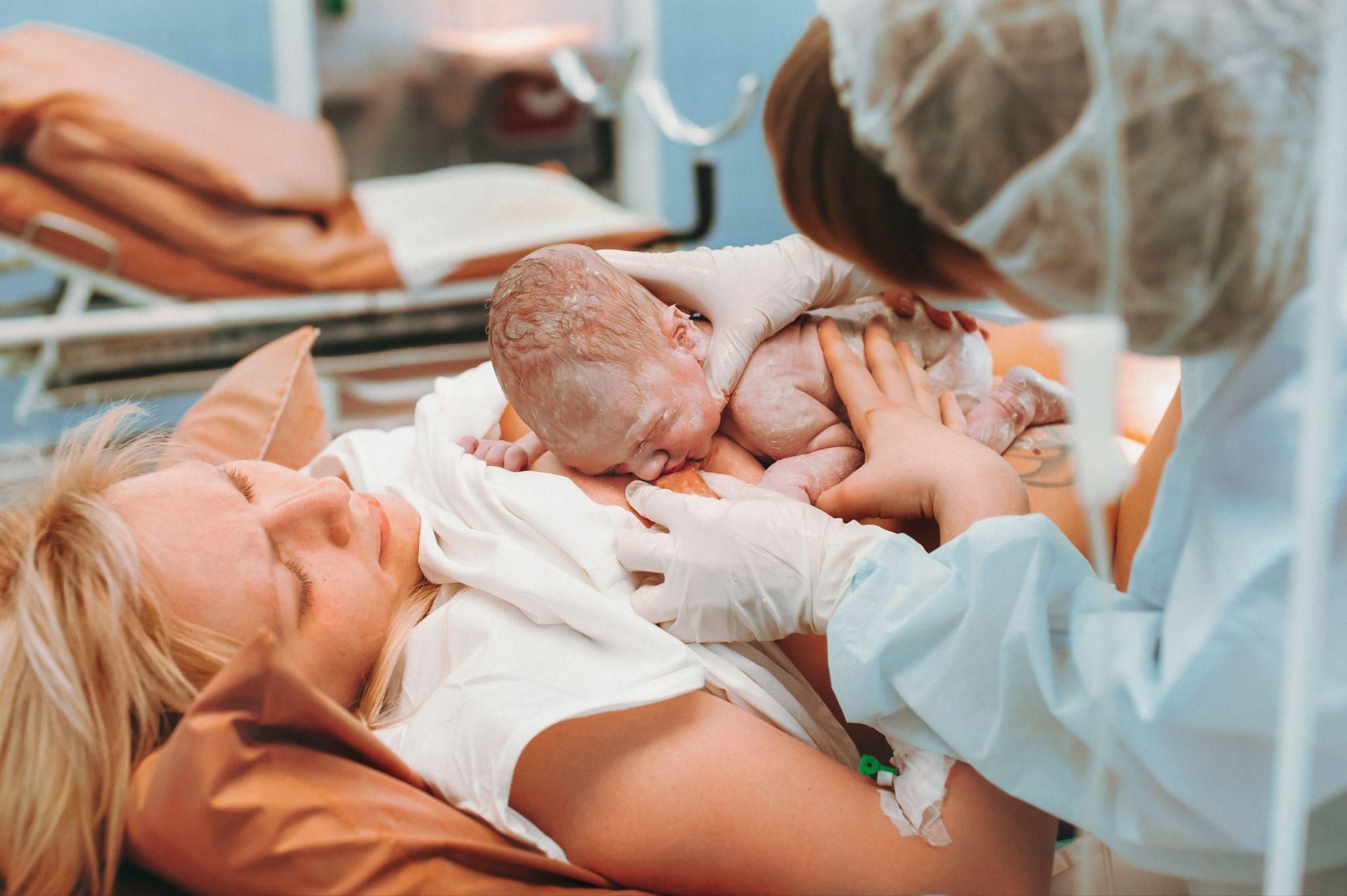 A mother lovingly holds her newborn baby in a hospital bed.