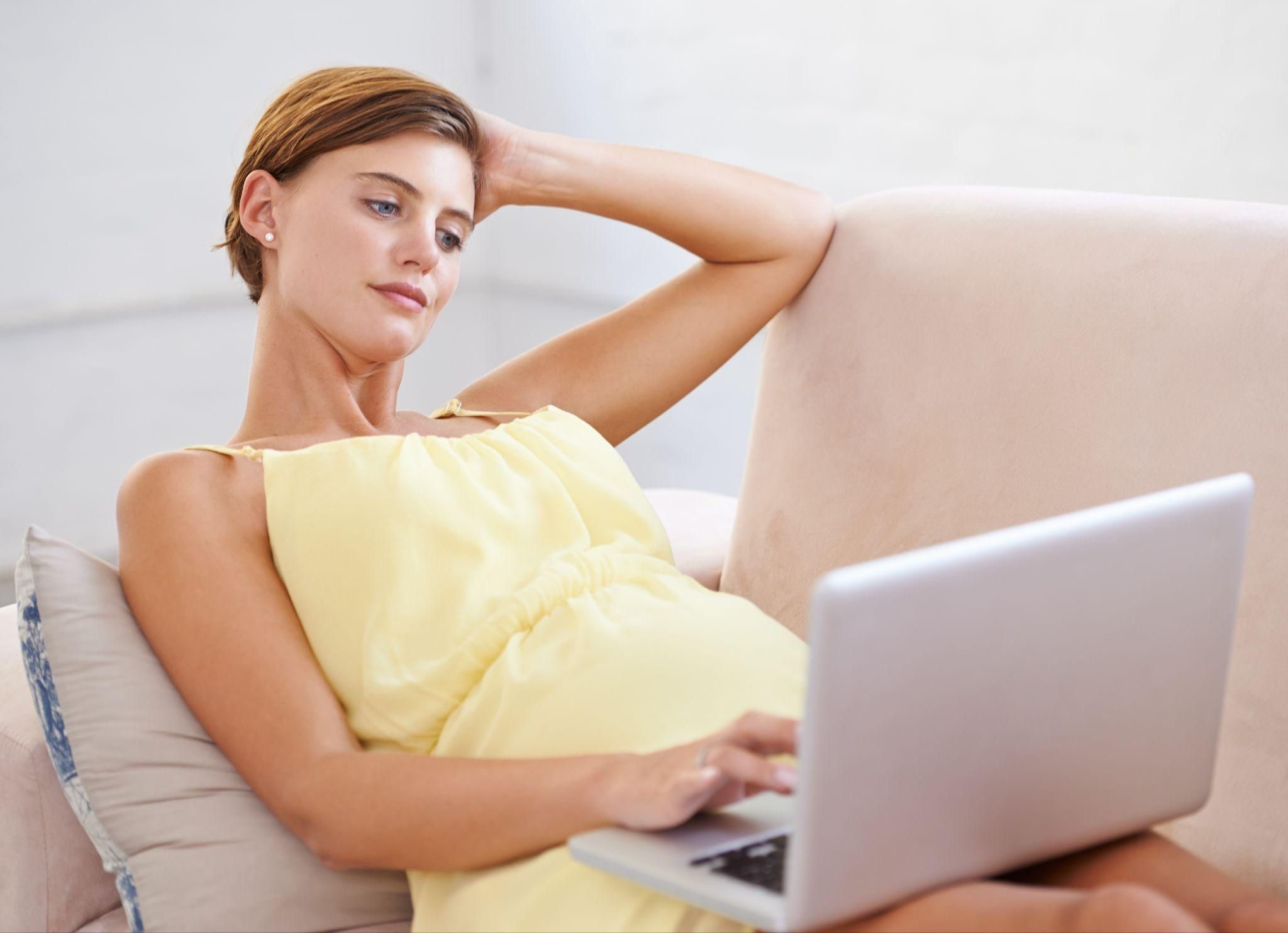 Pregnant woman researching NICE Guidelines on antenatal appointments on her laptop.