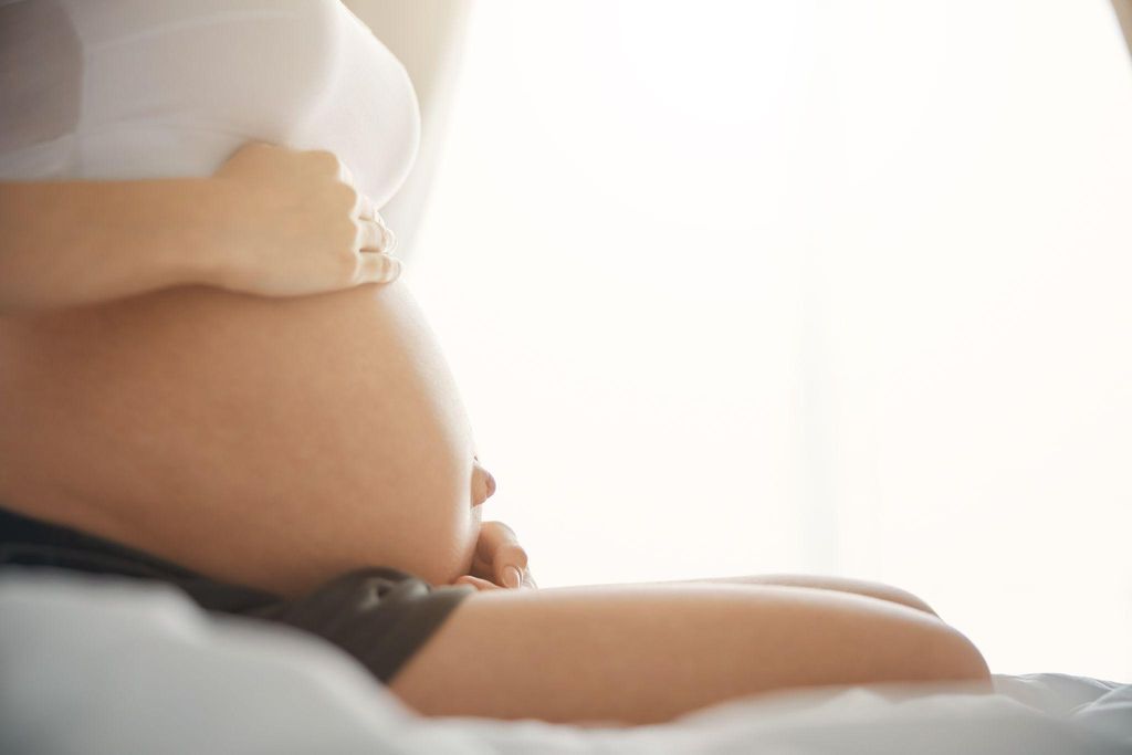 Expectant mother bonding with her unborn baby during pregnancy by touching her belly.