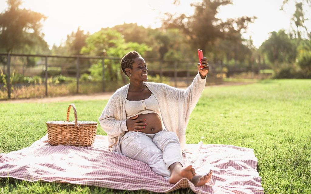 Pregnant woman enjoying an outdoor photoshoot in a park, surrounded by natural light.