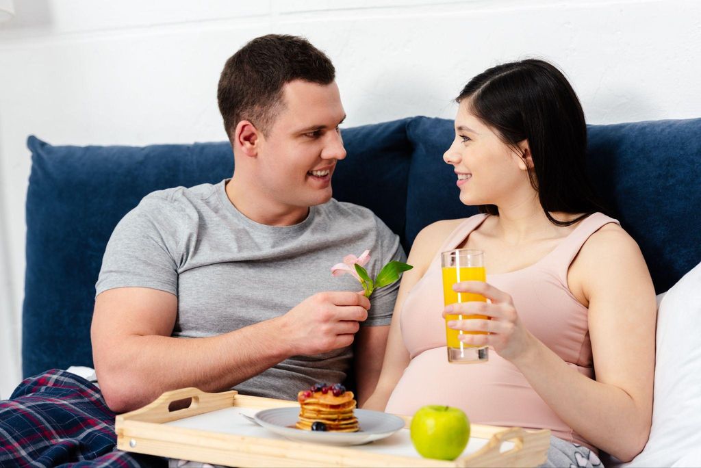 Pregnant woman eating pancakes with partner.